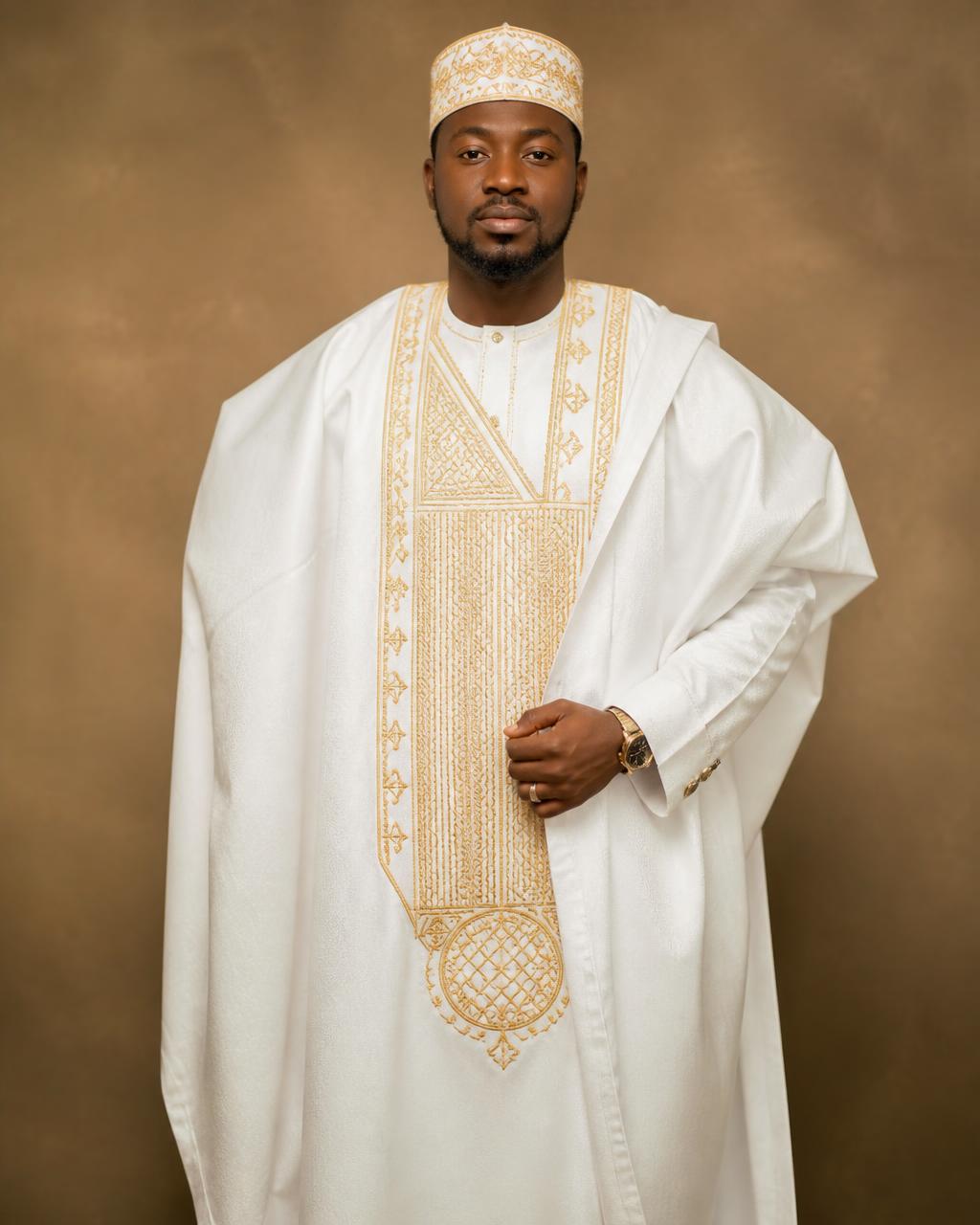 Man wearing embroidered white and gold agbada with matching cap